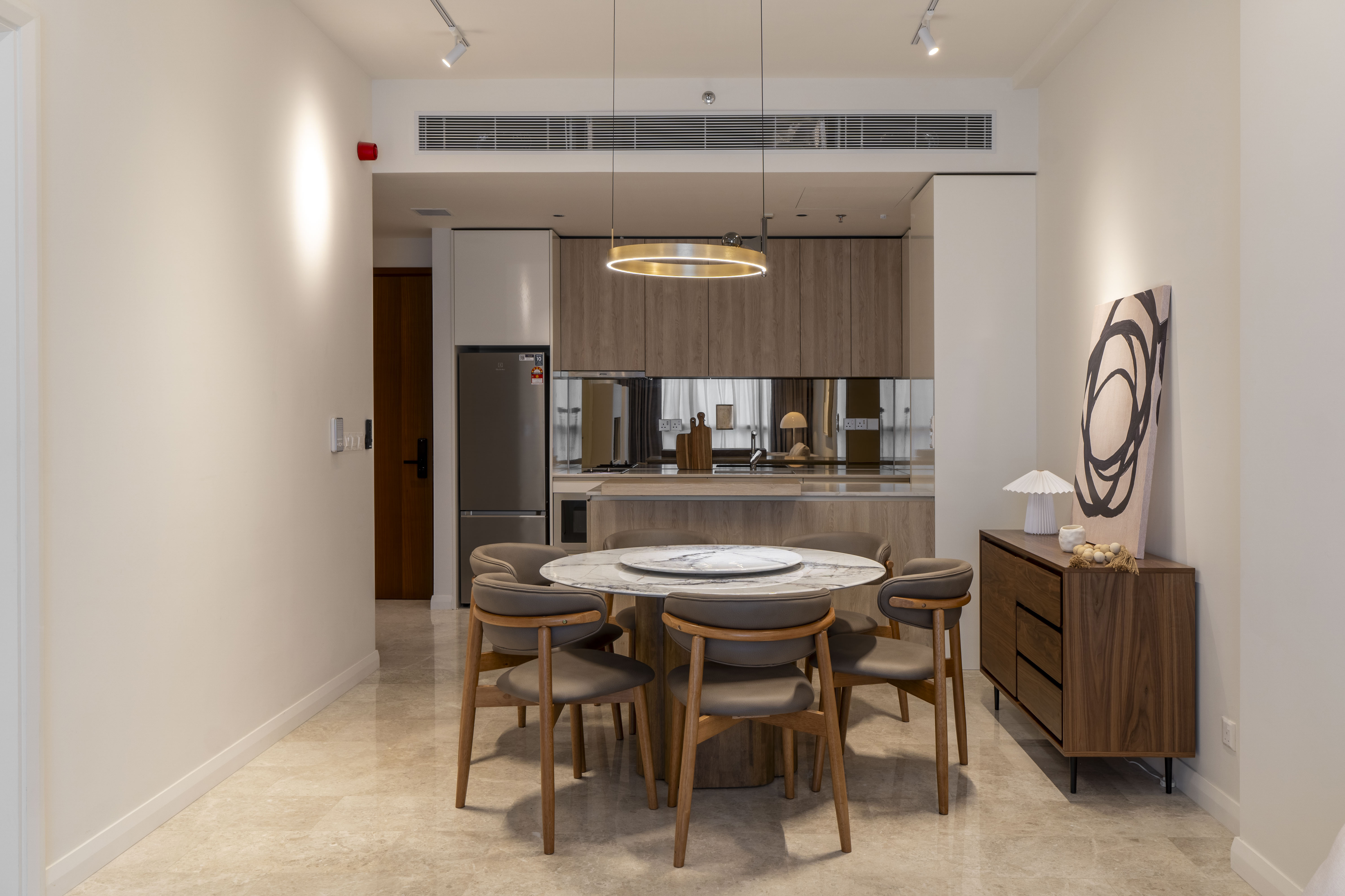 Round dining table beneath a circular pendant light at TRX Residence, Unit 01