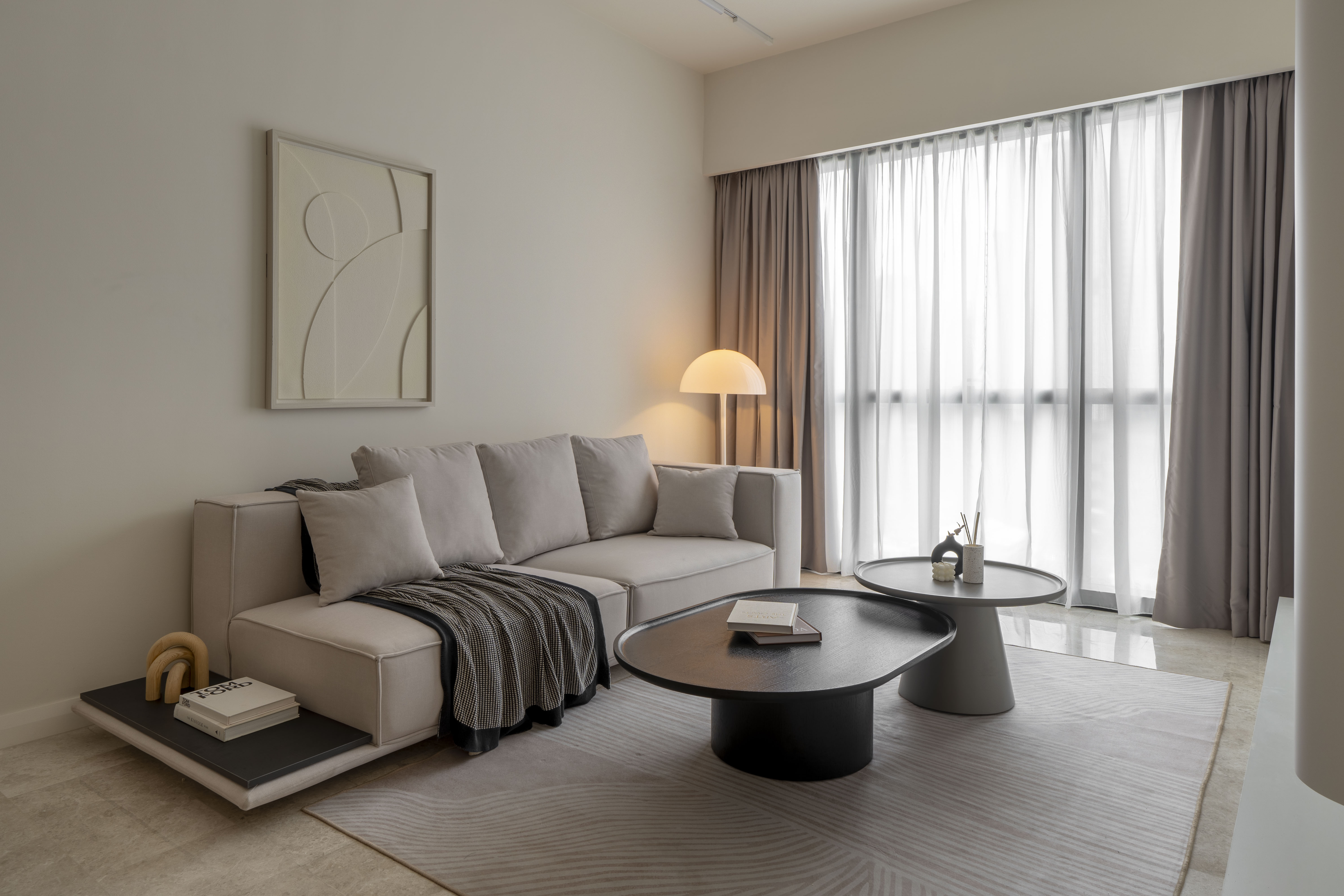 Grey sofa with nesting coffee tables and a warm floor lamp at TRX Residence, Unit 01