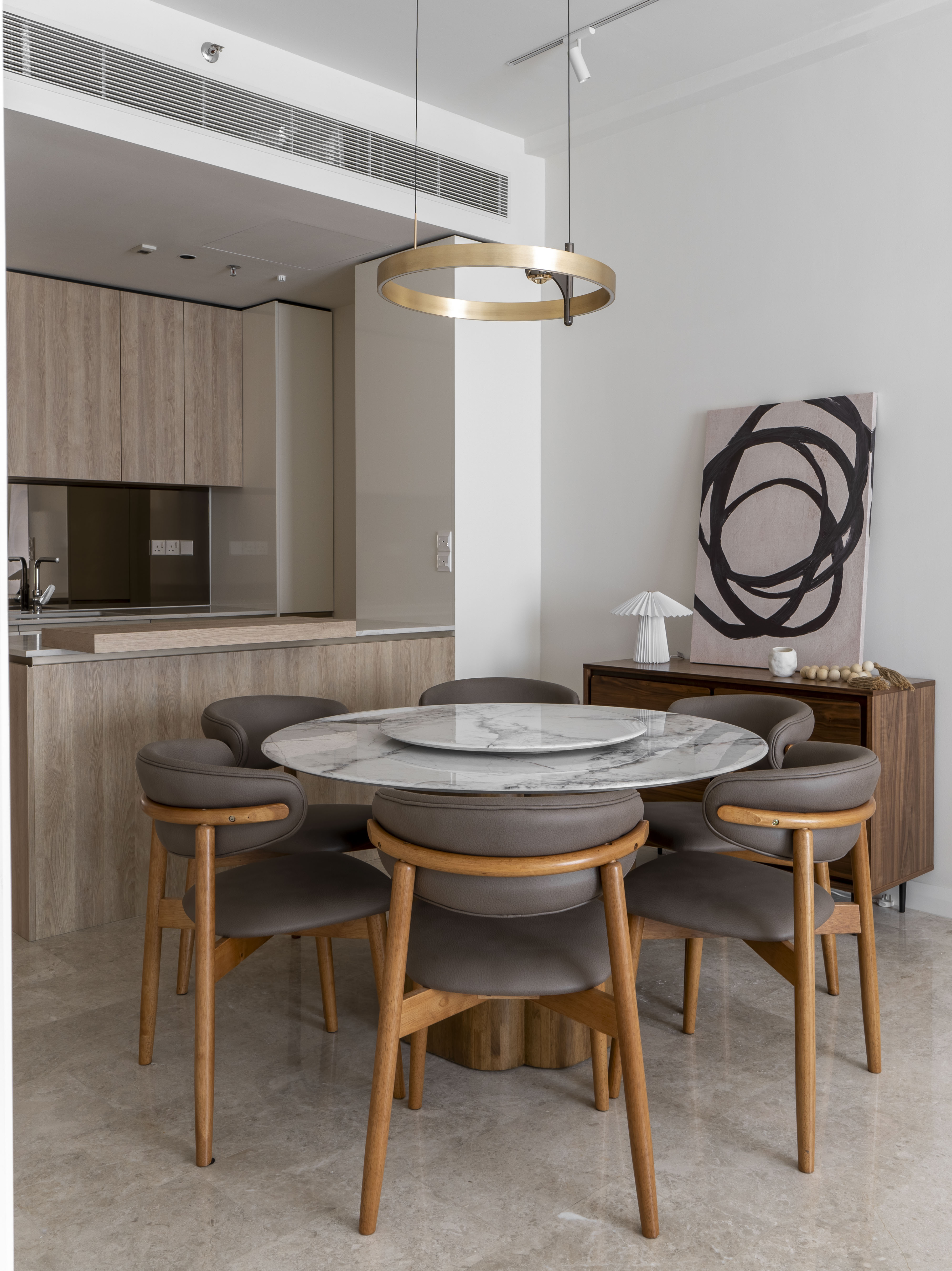Dining table and curved chairs beside abstract artwork at TRX Residence, Unit 01
