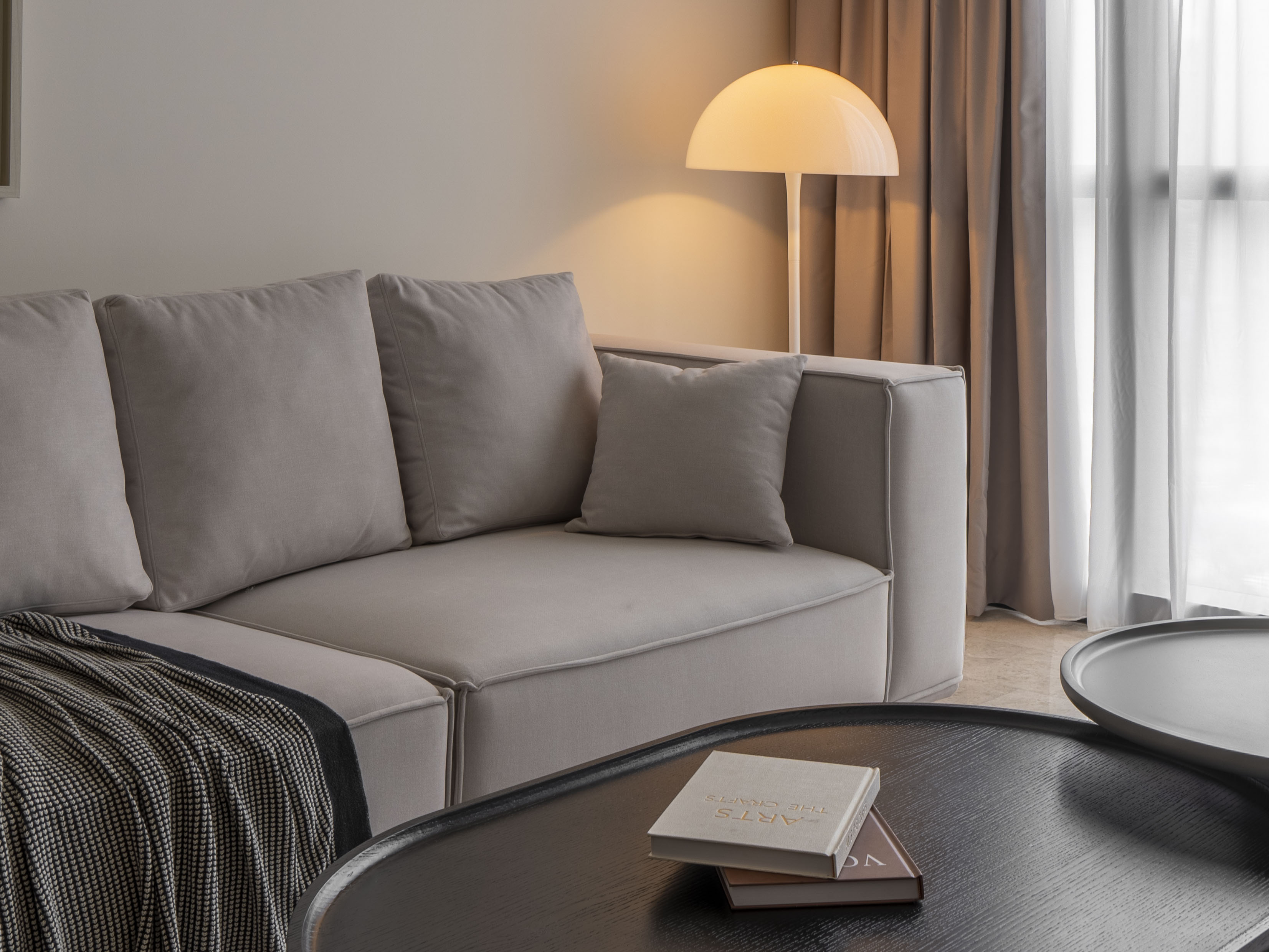 Sofa detail with a striped throw and dome-shaped floor lamp at TRX Residence, Unit 01