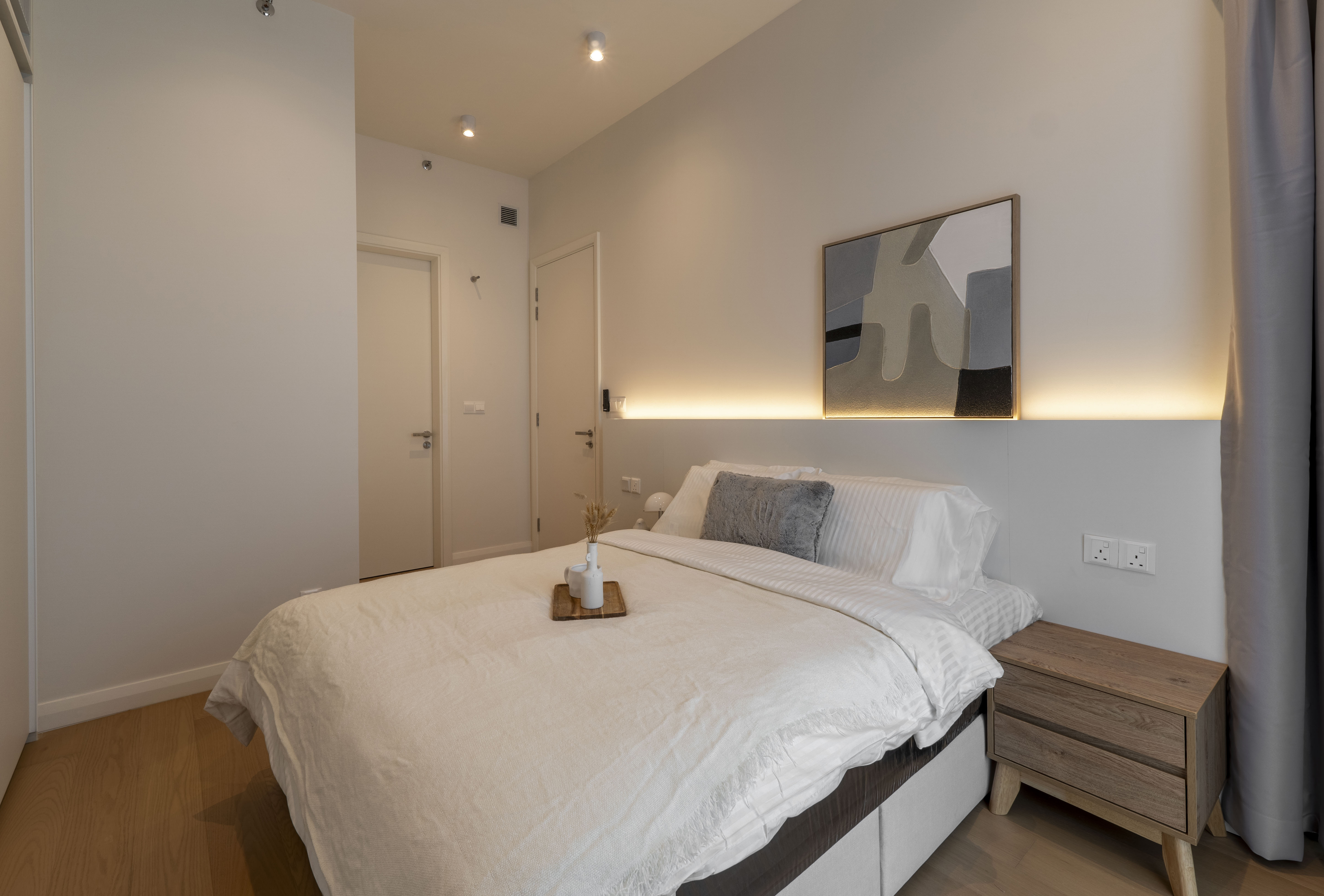 Warmly lit bedroom with artwork above the bed at TRX Residence, Unit 01