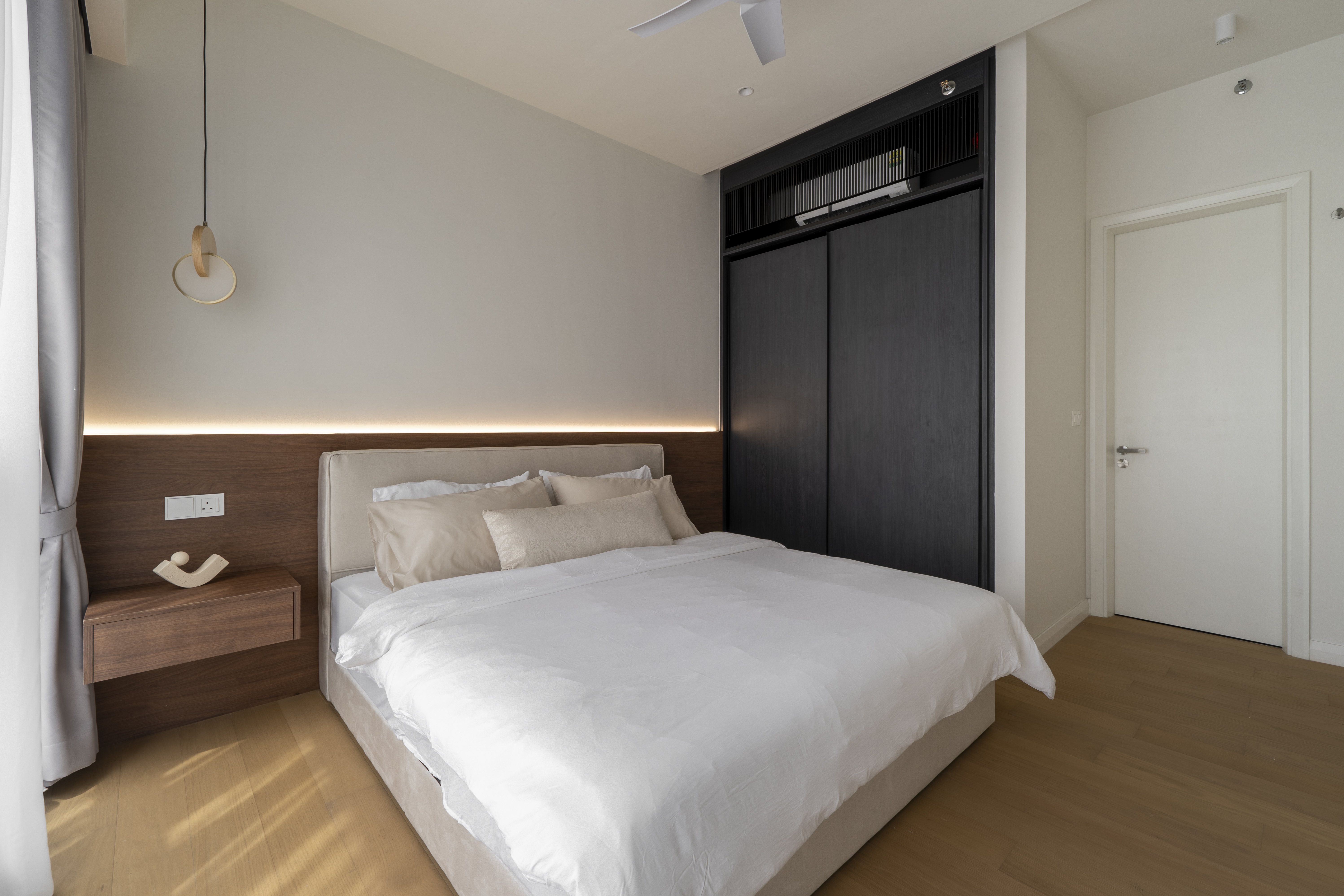 Bedroom with a timber headboard and dark built-in wardrobe at TRX Residence, Unit 02