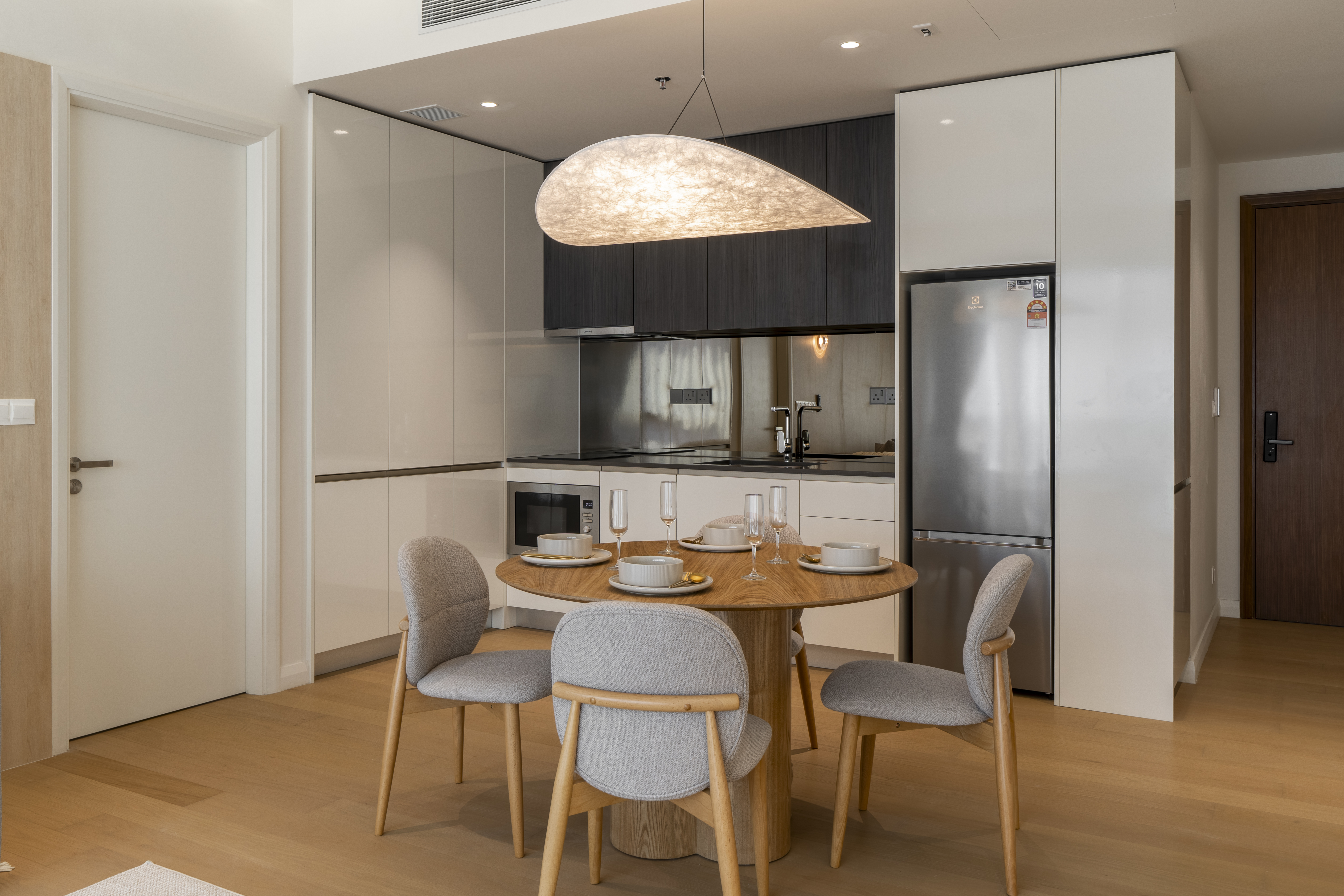 Dining table beneath a sculptural pendant beside the kitchen at TRX Residence, Unit 02