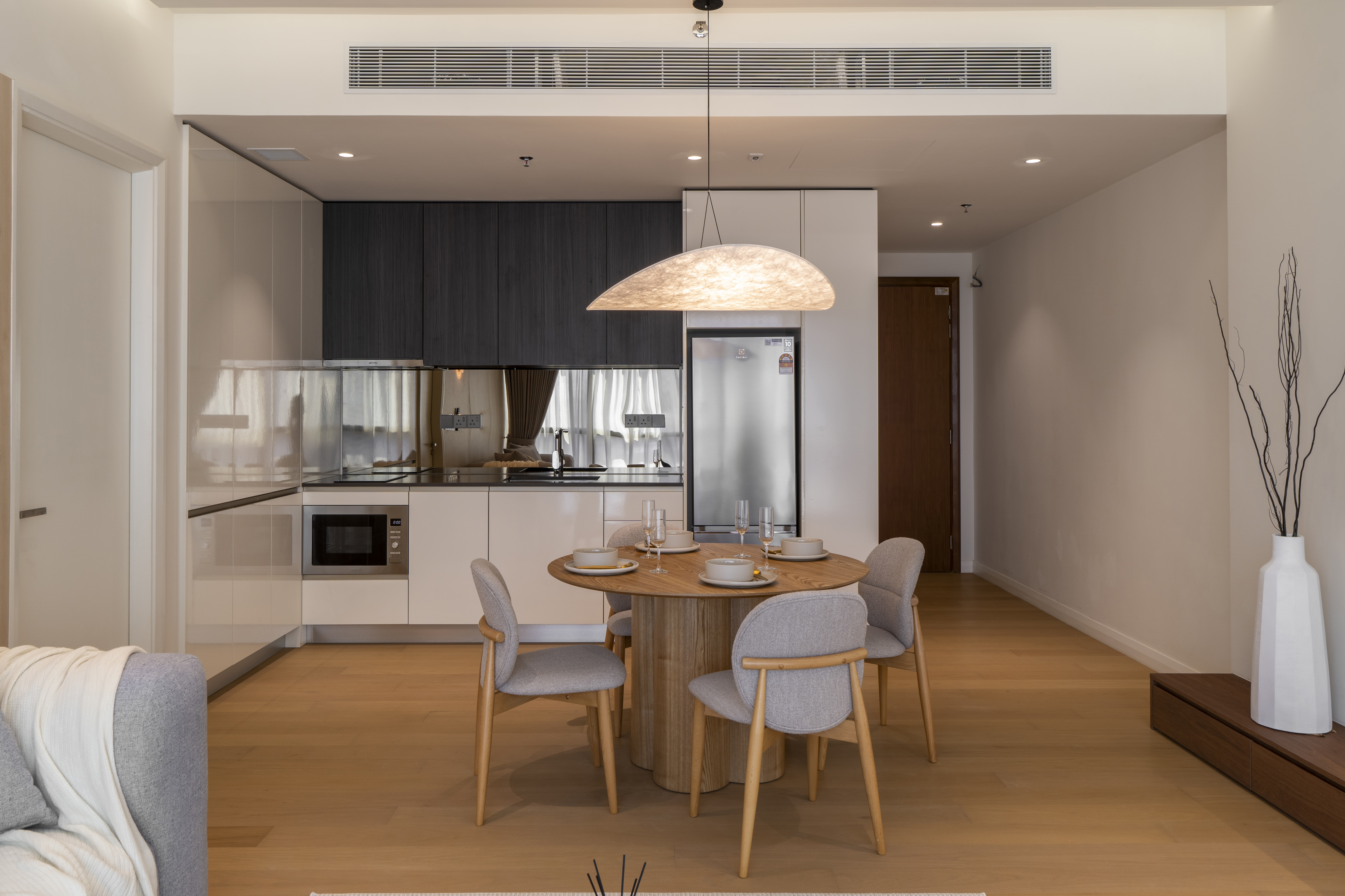 Compact kitchen with dark cabinetry behind the dining table at TRX Residence, Unit 02