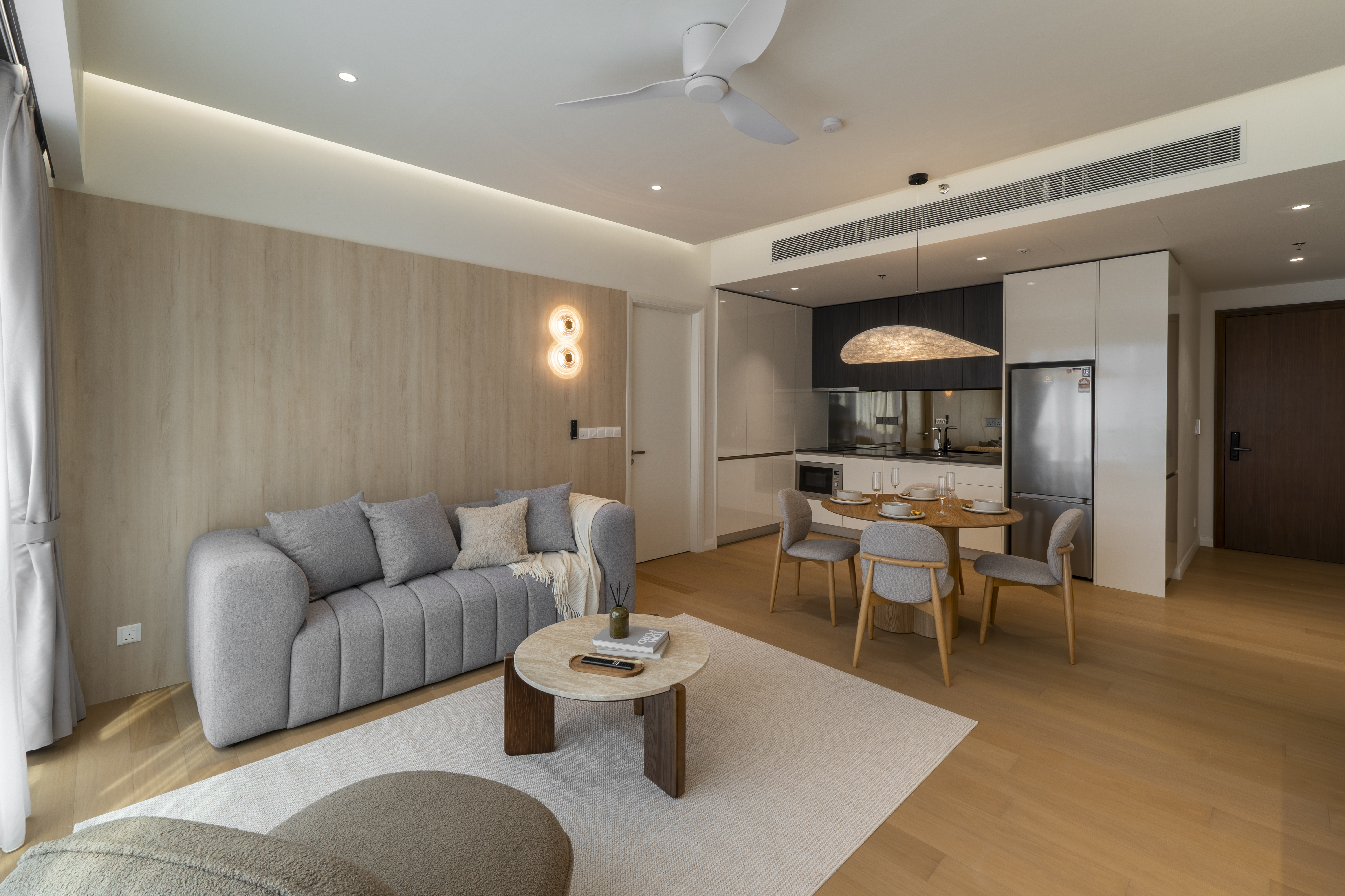 Grey sofa against a timber feature wall beside the dining area at TRX Residence, Unit 02